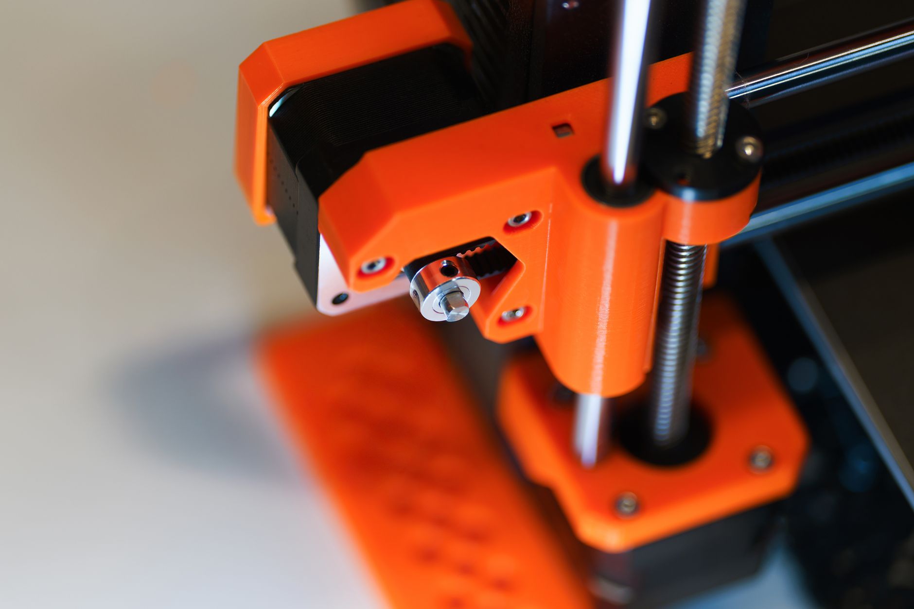 Close-up of a 3D printer Z-axis lead screw and adjacent orange frame.